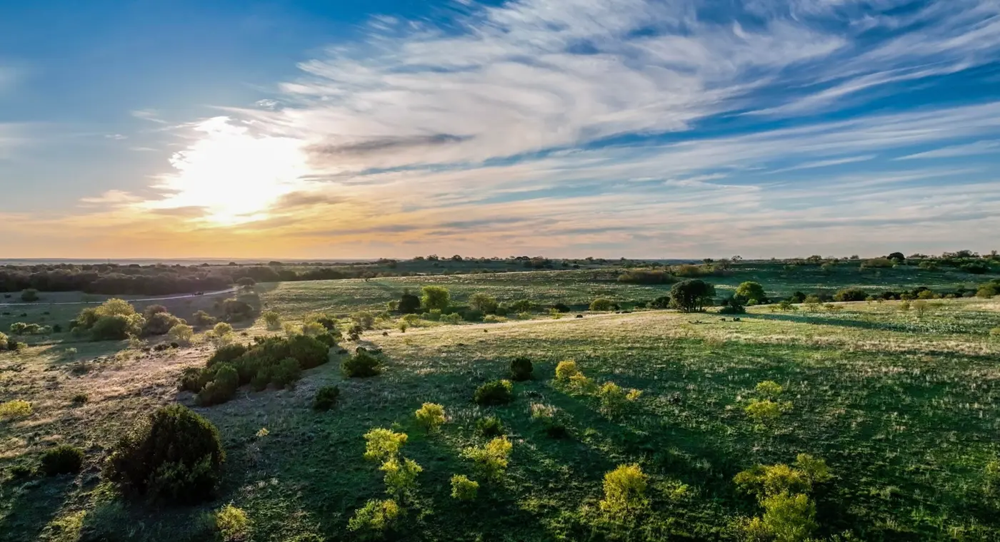 Aerial view of rolling green ranch land at sunset